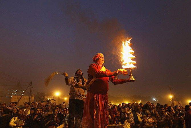 Hindu priest holds oil lamp as performs evening prayers near banks of river Ganges ahead of "Kumbh Mela" in Allahabad