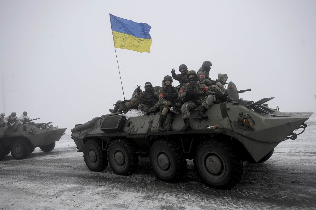 Ukrainian servicemen sit atop an armored personnel carrier as they patrol Orekhovo village in Luhansk