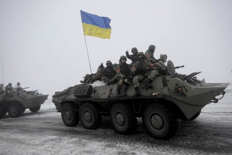 Ukrainian servicemen sit atop an armored personnel carrier as they patrol Orekhovo village in Luhansk